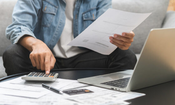 Person putting numbers into calculator looking at reports