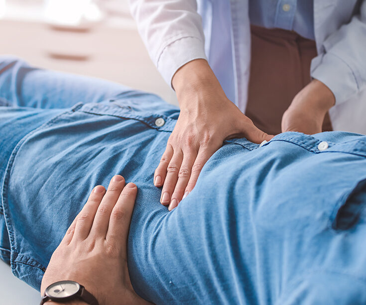doctor palpates stomach of patient
